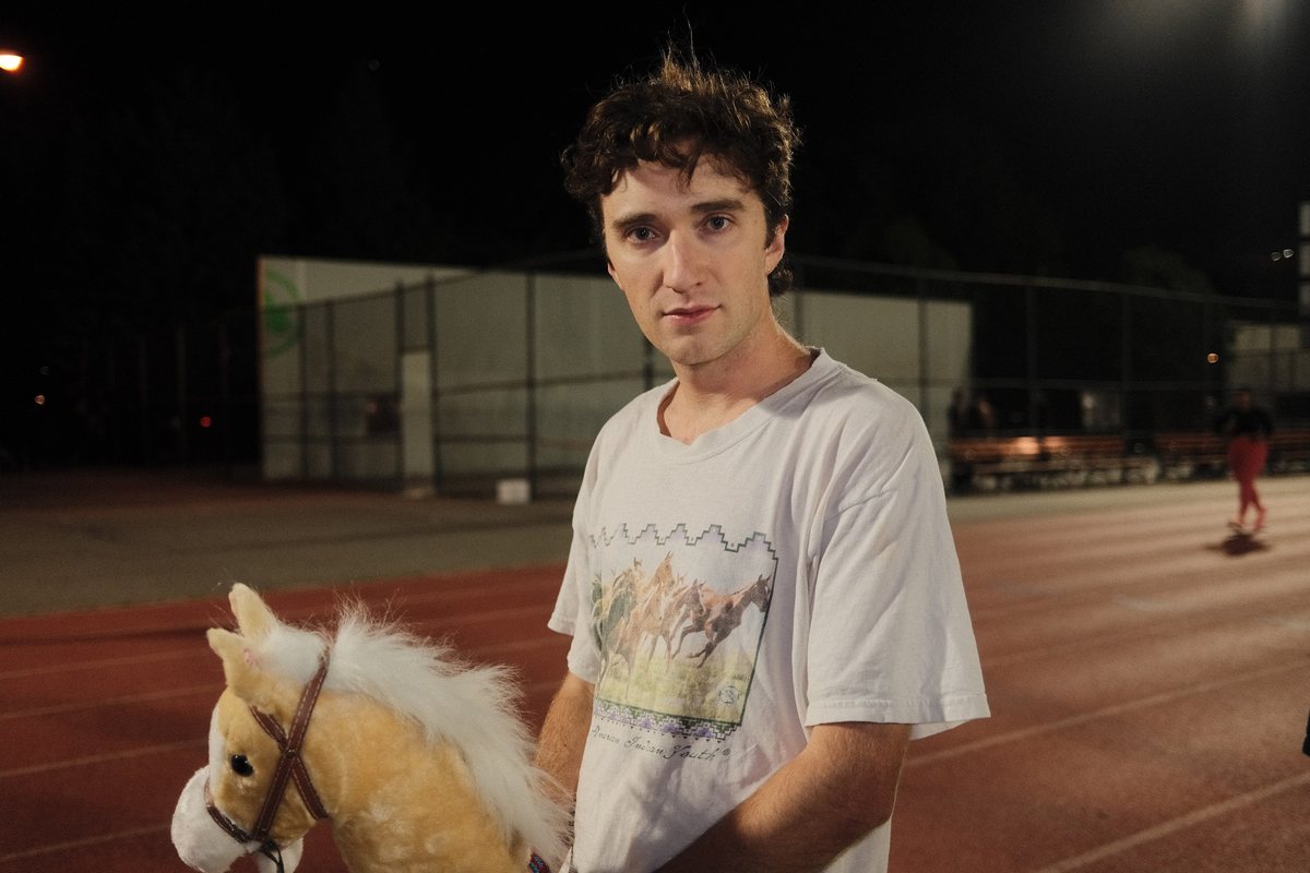 Holding a hobby horse on a floodlit running track at night